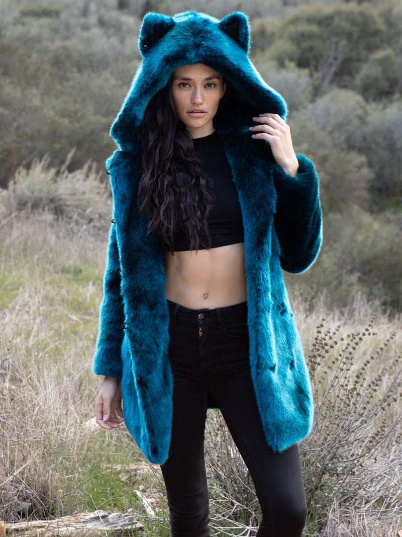 Dark-haired model outside in the brush wearing the Royal Wolf Luxe Classic faux fur coat, one hand on the hood.