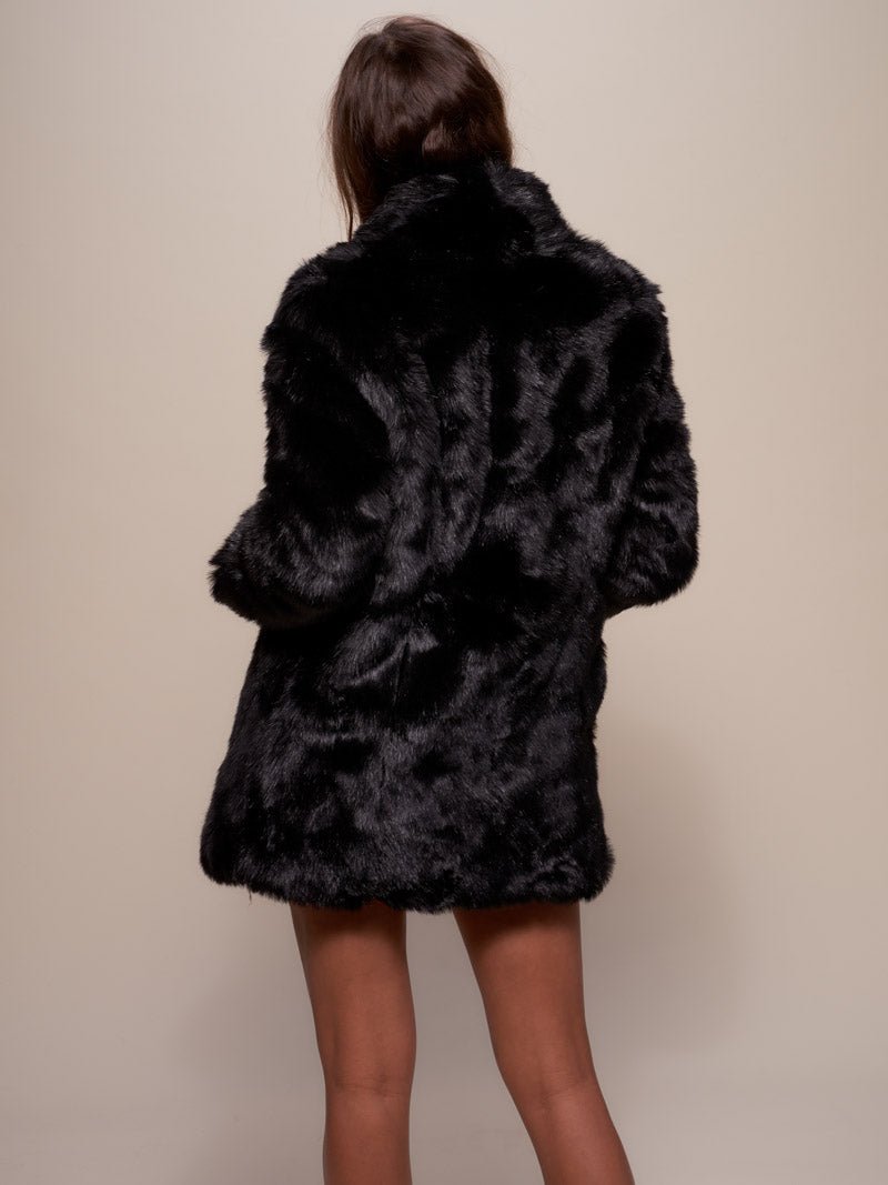 Brown haired girl with her back completely facing the camera wearing  vegan fur black panther coat with a collar. 