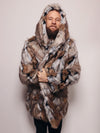 Bearded man wrapped in a Hooded Wolverine faux fur coat, holding it closed at the midsection with the hood up, looking happy and cozy.