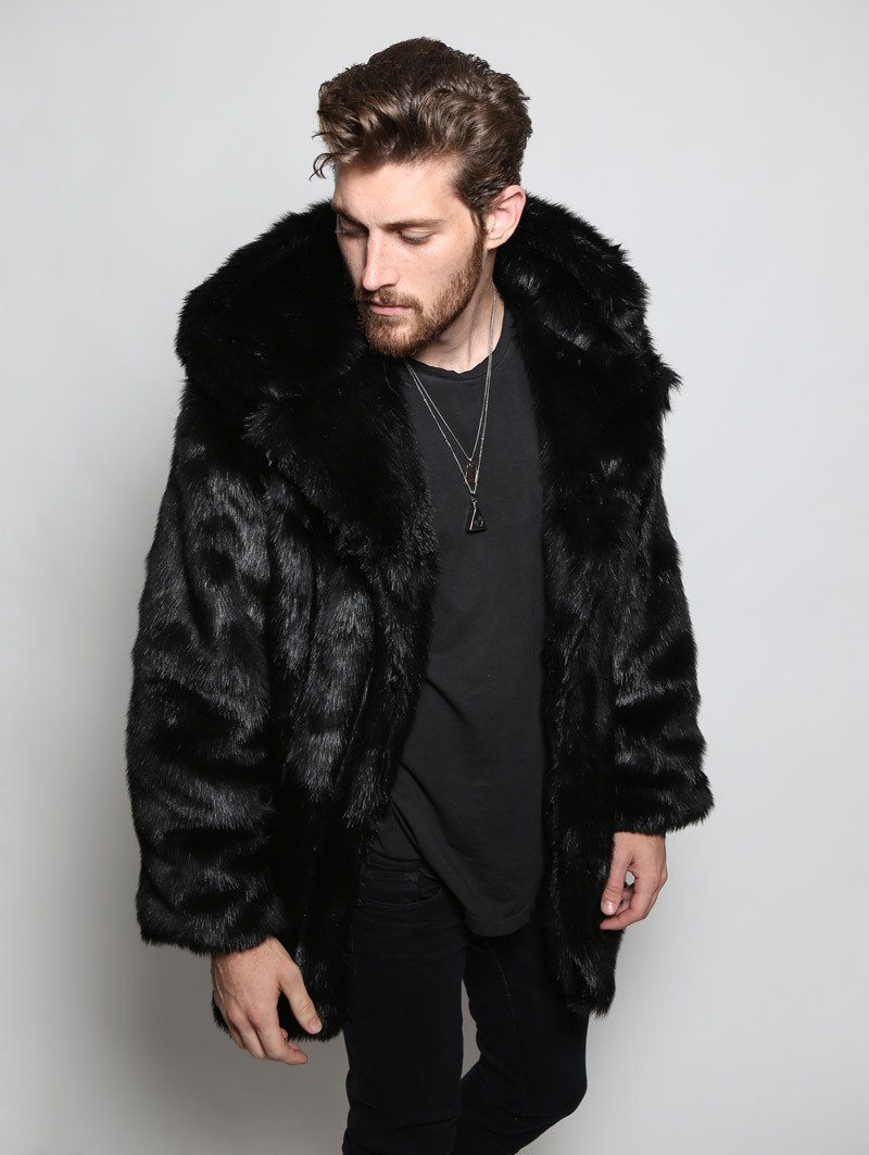 Young Male model wearing fake fur panther black coat looking slightly down and to the side with his arms to his sides.