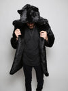 Male Model wearing a fake fur black panther coat holding the lapels with his hands while looking down with the hood and ears on his head. 