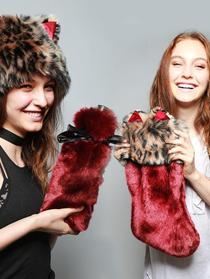 Women holding faux fur stocking, faux fur drink holder, and wearing faux fur hood